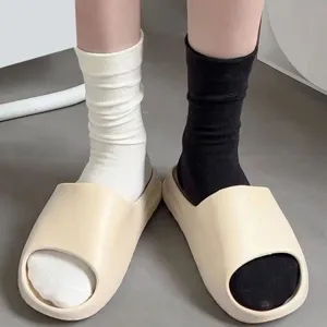 Women solid color slouch socks paired with thick platform slide slippers for casual wear.