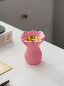 Gros plan d'un brûle-encens en résine rose créatif avec bol intérieur doré, détail de décoration.