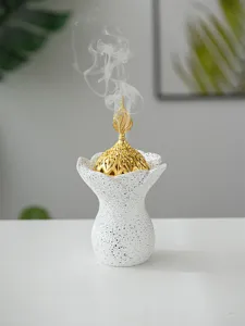 Vue détaillée de l'élégant brûleur d'encens oriental avec un couvercle doré délicat et texturé.