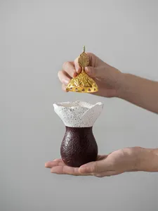 Gros plan d'un brûleur d'encens oriental moderne en résine avec un couvercle doré détaillé.