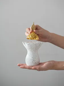 Brûle-parfum style oriental en résine avec corps tacheté blanc et couvercle doré élégant.