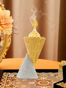 Close-up of a double cone Middle Eastern resin incense burner with golden hollow lid and smoke.