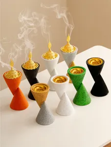 Detail view of colorful double-cone resin incense burners with golden hollow lids.