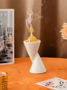 Close-up of twisted double-cone resin incense burner with gold lid and smoke effect.