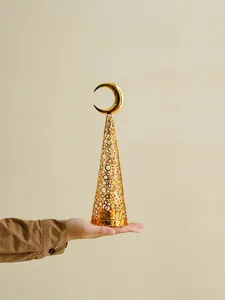 Detail view of a gold metal hollow Christmas tree candle holder with crescent moon top decor.