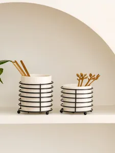Ceramic chopstick holder set with black metal wire frame and gold spoons for kitchen desktop.