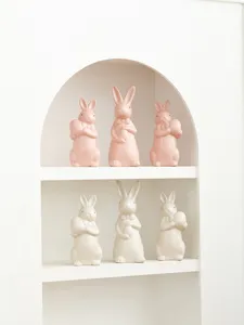 Ceramic Easter bunny figurine shelf display, cute pastel rabbit holding egg detail.