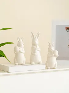 Detail shot of ceramic Easter bunny figurines holding eggs with cute bow ties for desktop decor.