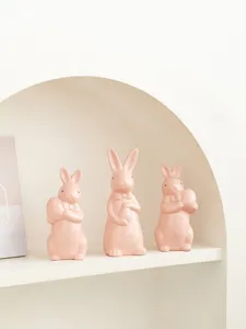 Detail view of cute ceramic Easter bunny figurines with bow ties and eggs, sweet desktop decor.