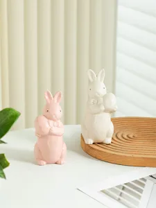 Easter ceramic bunny figurine holding egg, cute home desktop decor detail display style.