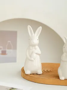 Detailed view of cute ceramic Easter rabbit figurine holding egg with bow tie for home decor.