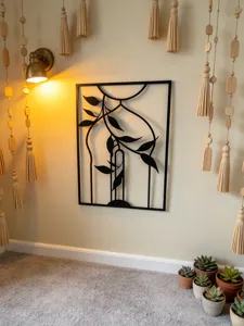 Metal wall art decor detail view featuring abstract leaf design in warm home lighting setup.