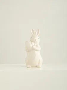 Ceramic Easter bunny figurine with bow tie and egg close up view for home desktop decor