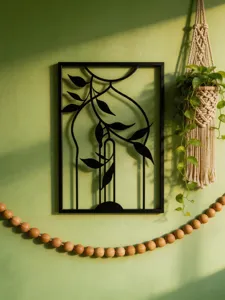 Close-up of black metal wall art featuring elegant leaf vine design for home decor detail.