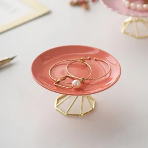 Modern minimalist ceramic jewelry tray with gold metal stand for desktop storage.