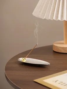 Detail shot of modern minimalist silver leaf incense holder with gold sphere stick base.