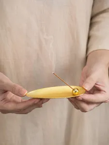 Detailed close-up of a modern golden willow leaf incense holder with a small sphere bead.