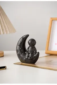 Detailed view of the creative black ceramic astronaut sitting on a moon ornament desk decor.