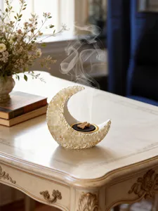 Detail shot of an elegant resin crescent moon incense burner on a vintage wooden table.