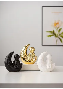 Detail shot of modern ceramic astronaut moon ornaments in black, gold, and white colors.