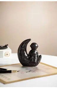 Detail view of modern creative ceramic astronaut moon ornament, home desktop decor craft.