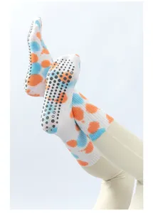 Close-up view of colorful tie-dye yoga grip socks with anti-slip rubber dots on soles for indoor fitness.
