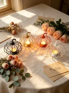 Detailed view of metal pumpkin tealight candle holders on a romantic table setting with roses.