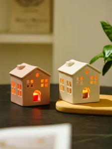 Ceramic house candle holder detail, minimalist modern home decor, cozy tabletop accent lighting.