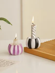 Close-up detail view of resin pumpkin candle holders with burning candles on a wooden tray.