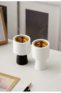 Modern ceramic incense burner detail view, minimalist table decor with gold inner dish and smoke.