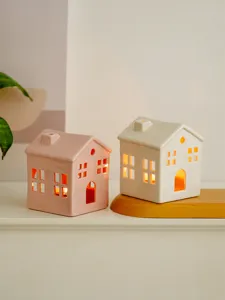 Close-up detail view of ceramic hollow house candle holders with warm light for home decor.