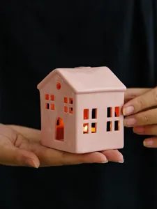 Ceramic house candle holder detail view, pink hollow design for home decor table.