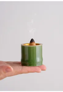 Vista di dettaglio di un mini bruciatore di incenso in ceramica di bambu verde in mano.