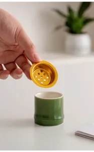 Primo piano del porta incenso in ceramica verde a forma di bambù con accessorio dorato.