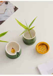 Primo piano dettagliato del bruciatore di incenso in ceramica verde con accessori dorati.