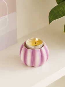 Detail view of purple and white resin pumpkin candle holder with tealight candle, festival decor.