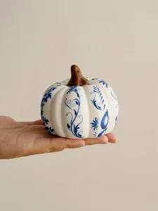Close-up detail shot of a ceramic blue and white porcelain pumpkin ornament held in hand.
