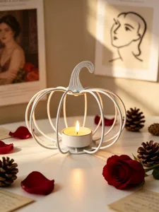 Detail view of white metal pumpkin candle holder with tea light, styled with autumn roses.