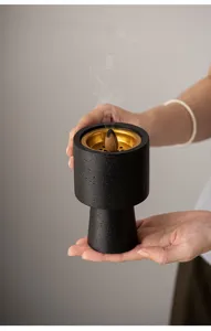 Detailed view of a modern black textured incense burner showcasing a gold inner bowl and cone.