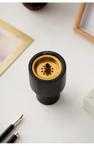 Modern black textured aromatherapy burner with gold metal plate and burning incense cone for home decor