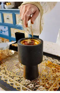 Middle Eastern Arabic style black matte incense burner detail view with resin incense and tongs.