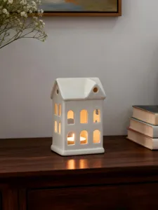 Vue détaillée d'un porte-bougie chauffe-plat en céramique blanche brillant chaleureusement.