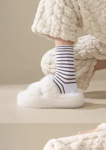 Close-up detail of soft breathable striped cotton mid-tube socks worn with cozy plush slippers.