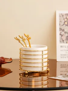 Ceramic tableware storage holder with gold wire rack and leaf spoons for desktop organization.