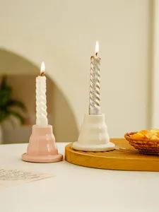 Close-up detail of ceramic candle holders with burning spiral candles on a cozy home desk.