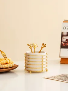Detail view of ceramic tableware storage holder with gold wire caddy and elegant leaf spoons.