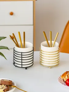 Ceramic cutlery holder set detail showing dual black and gold metal wire frames with spoons.