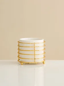 Detailed view of a white ceramic storage jar featuring an elegant gold metal wire stand.