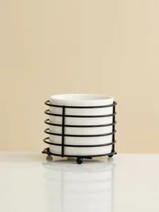 White ceramic storage jar with black metal wire rack, minimalist desktop organizer for utensils.