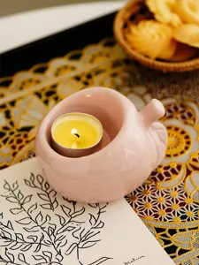 Pink ceramic candle holder detail, cute tealight cup with warm flame for tabletop decor.